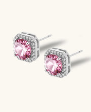 Pink moissanite studs in octagonal sterling silver halo settings with sparkling accent stones on cream background.
