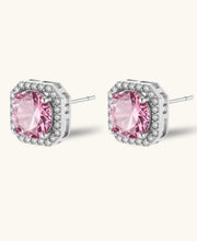 Pink moissanite studs in octagonal sterling silver halo settings with sparkling accent stones on cream background.